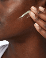 dark women applying cream on her face